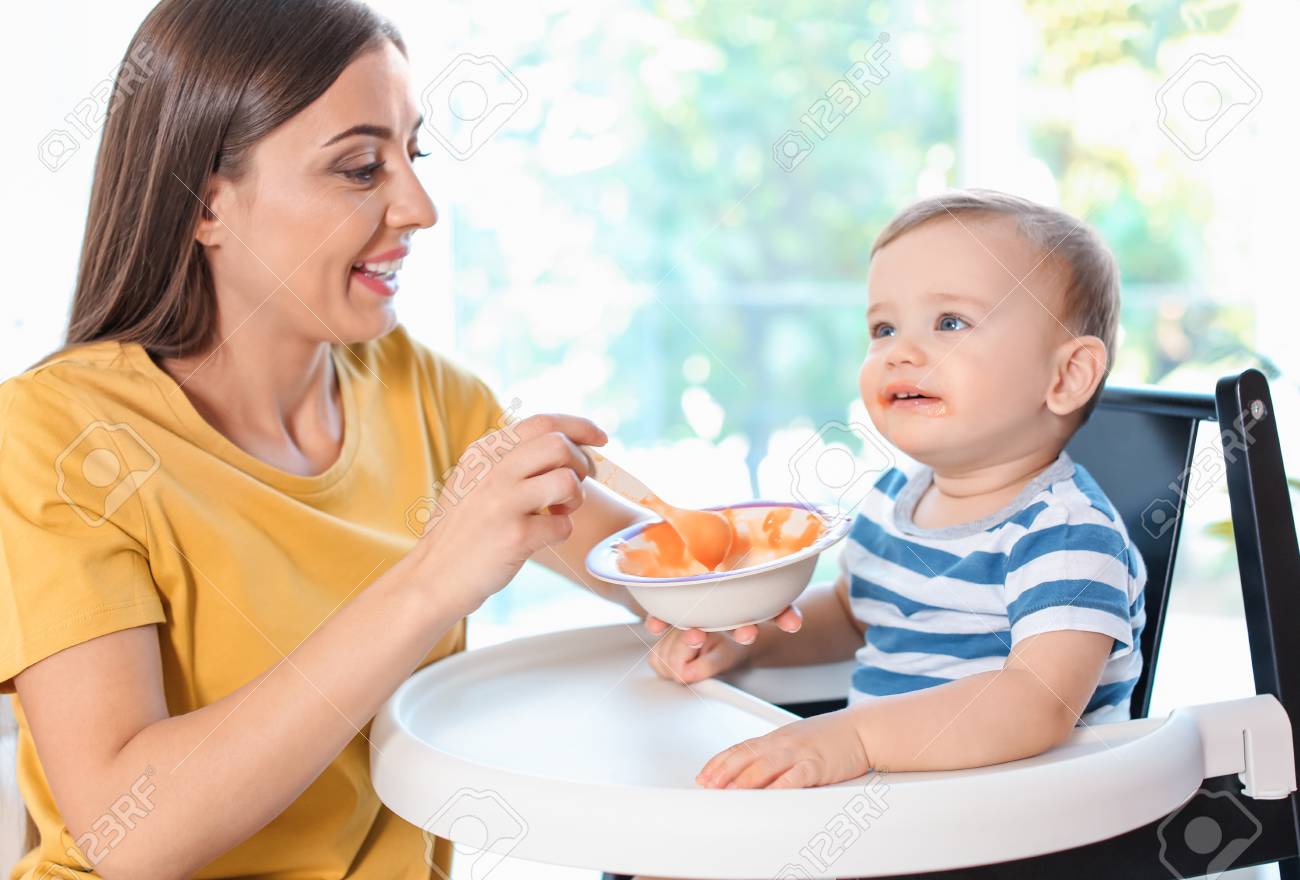 107793573 woman feeding her child in highchair indoors healthy baby food