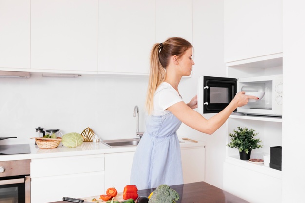 close up blonde young woman inserting food microwave oven 23 2148120488