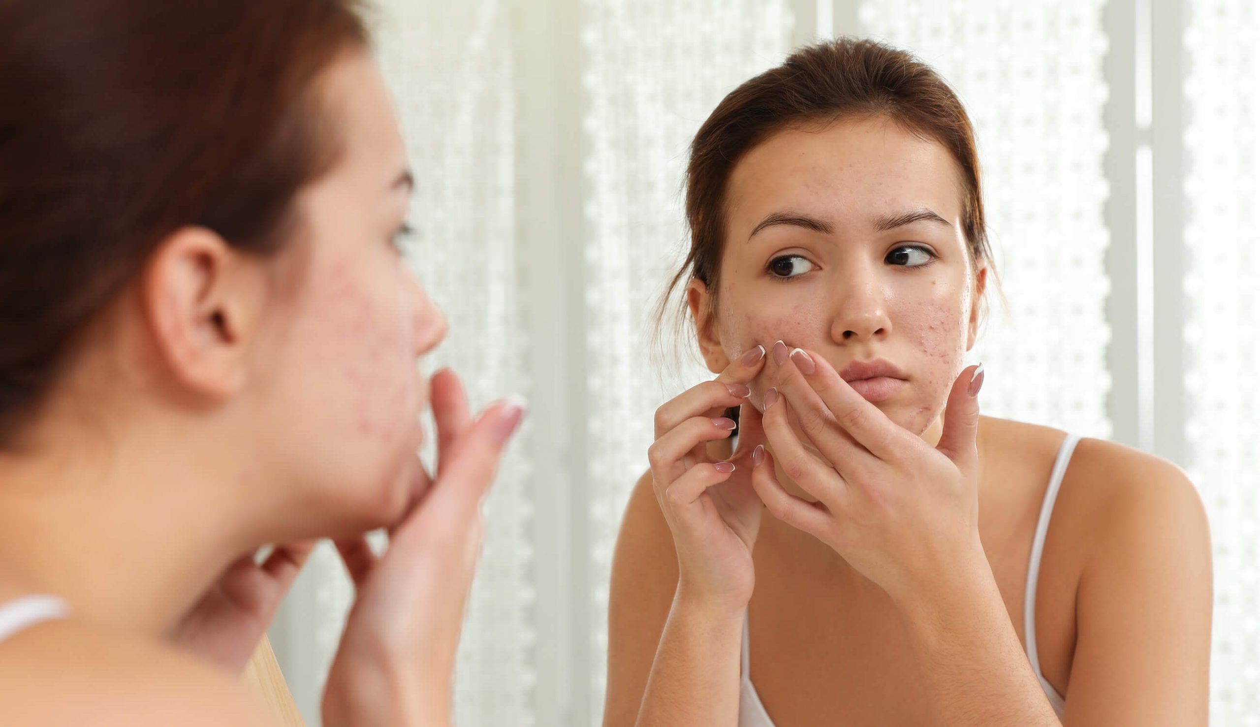 main woman inspecting face in mirror scaled