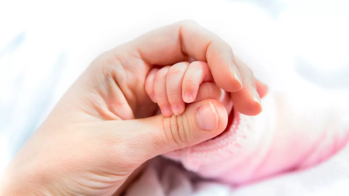0 Mothers hand holding newborn babys hand